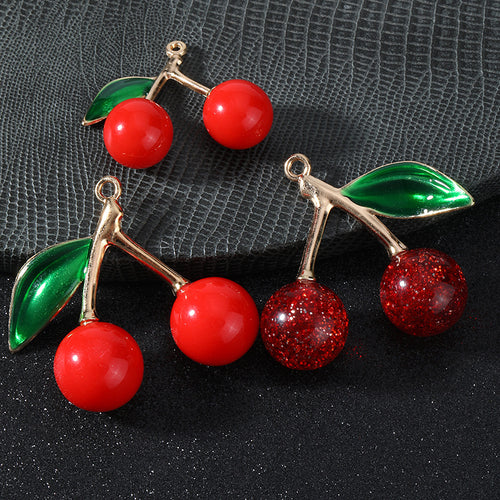 Group of cherry charms in glossy red, glitter red and solid red on a textured surface