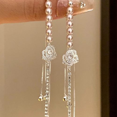 Close-up of silver rose charm bracelet ends with pink pearls and rhinestone chains