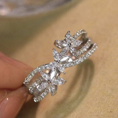 Close-up of silver marquise flower ring held between fingertips