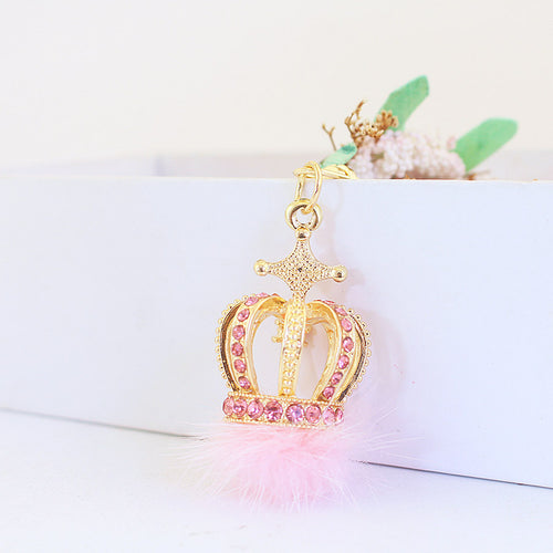 Rear view of the pink rhinestone crown charm above a fluffy pink pom pom.