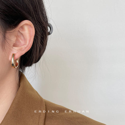 Polished chunky C-hoop earrings in silver and gold tone shown worn on an ear.