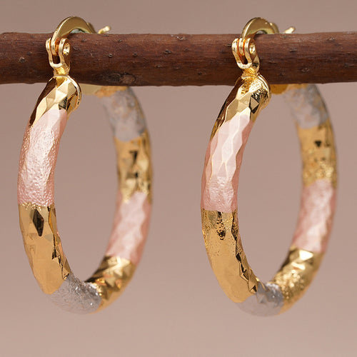 gold tone earrings showing medium round hoops with irregular pink sections