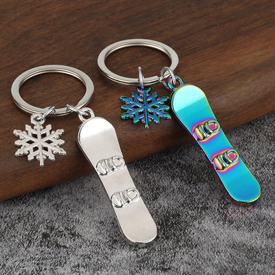 Silver and rainbow snowboard keychains displayed together on a wooden surface