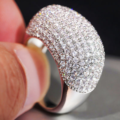 White gold full pave dome ring held between fingers close-up