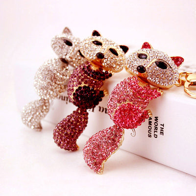 Three rhinestone fox keychains in pink, purple, and white displayed together.