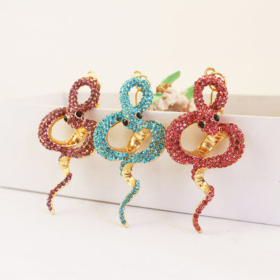 Three coiled snake charms covered in purple, blue, and pink rhinestones.