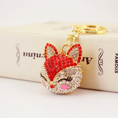Red rhinestone fox keychain resting against a cream box.