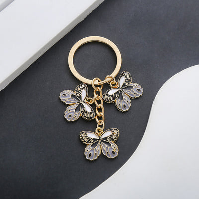 Front product photo of black butterfly enamel charm keychain with gold tone hardware showing the pictured design arrange