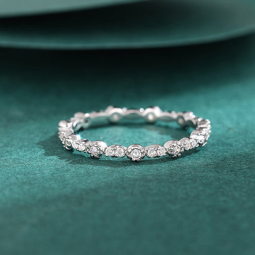 Clear stone scalloped band ring on green velvet surface