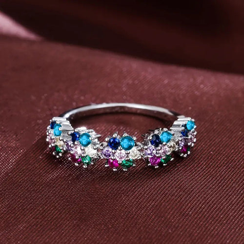 Silver multicolor flower cluster ring on dark burgundy fabric