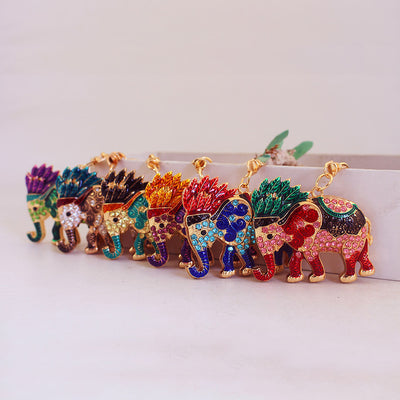 Six colorful elephant keychains stand in a row with different stone and patterned color combinations.