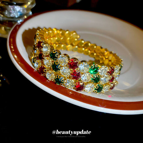 Gold multicolor rhinestone open cuff resting on ceramic plate