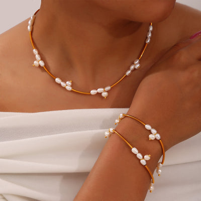 Model wearing gold tube baroque pearl necklace and stacked bracelets