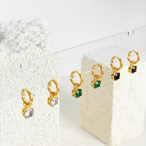 Row of gold huggie drop earrings clear green and black stones