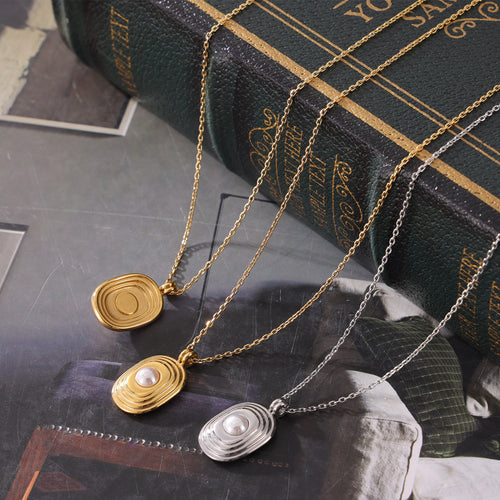 Gold and silver concentric oval pearl pendants on books