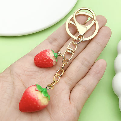 Image 1 showing a hand holding two strawberries.
