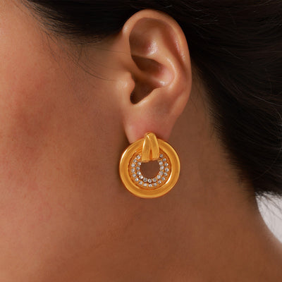 Gold hollow circle stud earring with rhinestone center worn on ear