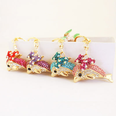 Four gold-tone dolphin keychains with red, purple, blue, and pink rhinestone details.