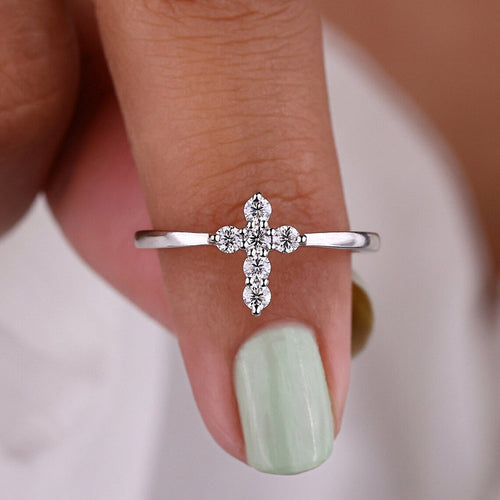 Silver clear stone cross ring worn on finger tip close-up