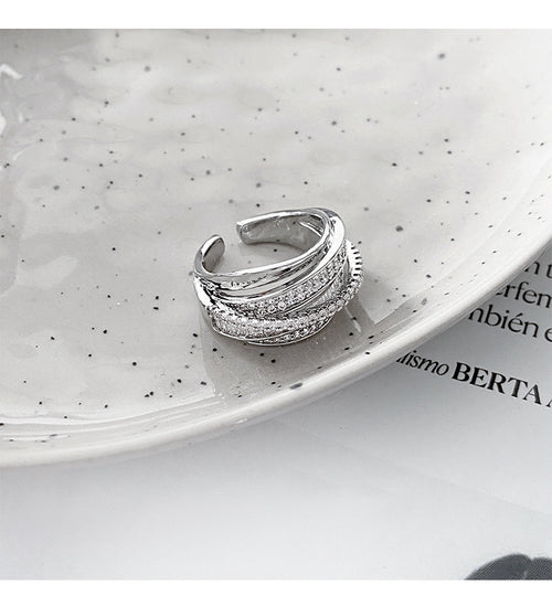 Silver multi-band open crossover pavé rhinestone ring on speckled plate