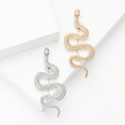 Silver and gold textured scale snake brooches on white platforms