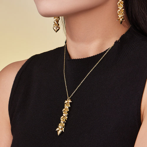 Model in black top wearing gold multi-heart necklace and drop earrings