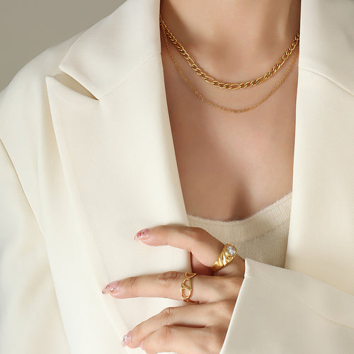 Gold double-layer Figaro and fine chain necklace on cream blazer