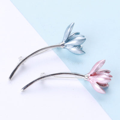 A long curved tulip stem with a colored bloom shown on a white background