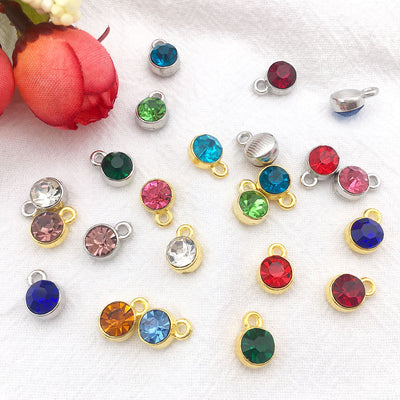 Metallic birthstone charms arranged on a light background