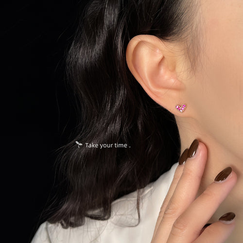 Model wearing tiny pink crystal heart stud on ear