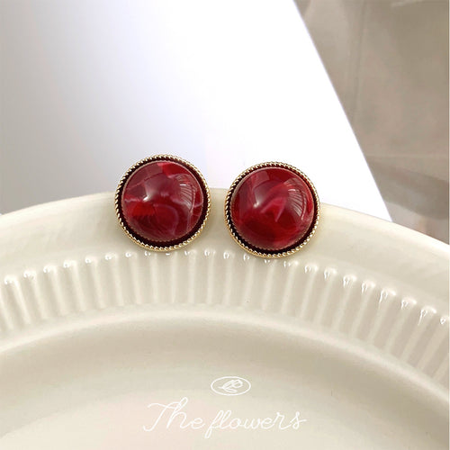 Deep red marbled resin studs on white ceramic plate