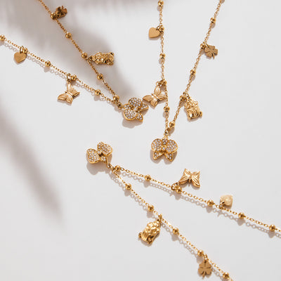 Gold multi-charm necklaces flat lay with pavé bows butterflies hearts clovers beetles