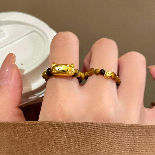 Gold cat-face and coin charm tiger eye bead rings on fingers
