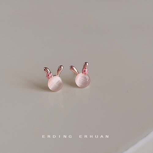 Rose-gold-tone rabbit-ear pink-pearlescent studs in the first product display.