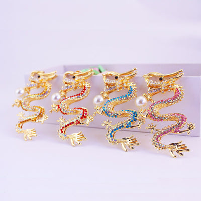 Four gold-tone dragon keychains with different rhinestone colors and pearl-look bead accents.