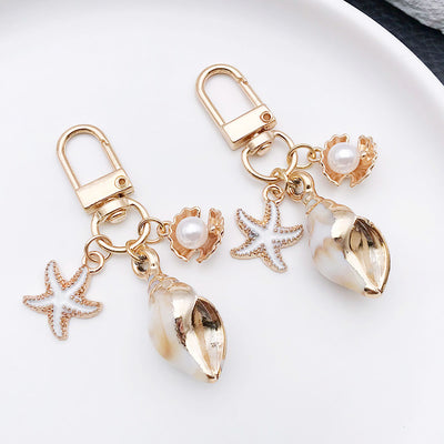 Main display of gold tone starfish conch scallop and pearl-look clasp charms