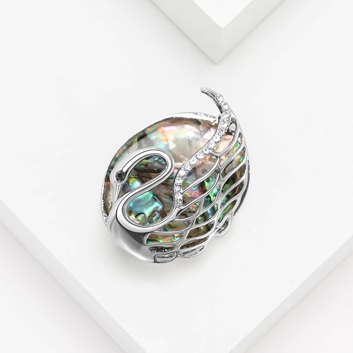 Abalone swan brooch angled on white geometric blocks