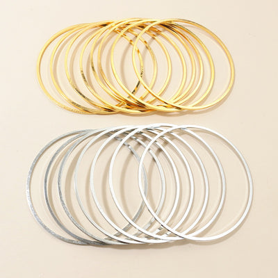 Overview of thin oversized hoop earring findings in gold and silver tones on a light background