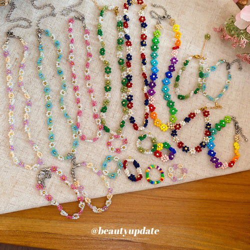 Assorted seed bead daisy flower necklaces bracelets and rings on linen fabric