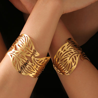 Gold hollow leaf open cuff bangles worn on both wrists