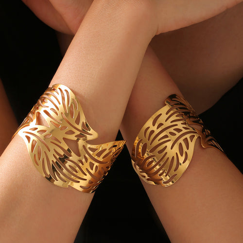 Gold hollow leaf open cuff bangles worn on both wrists