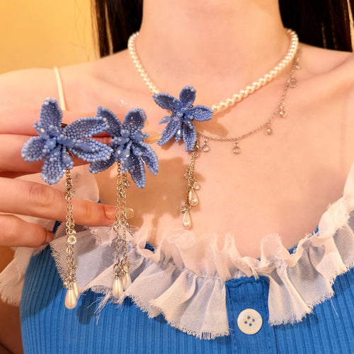 Model wearing blue bead flower pearl necklace and holding matching earrings