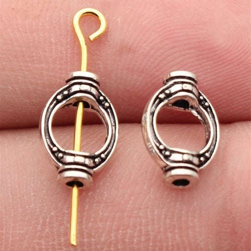 Open oval connector with dotted border details and loops at both ends shown close up on a hand
