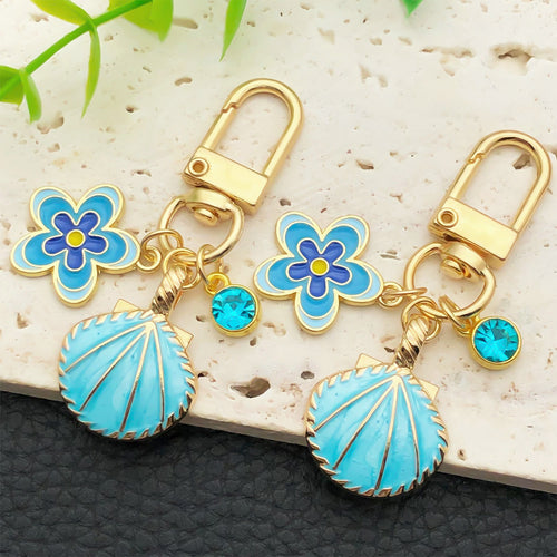 Styled close-up of shell flower and rhinestone u clip keychain showing colors and surface details