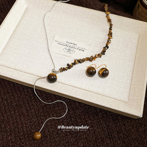 Tiger eye chip snake-chain necklace and bead earrings on beige tray