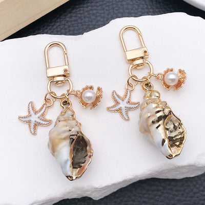 Main display of four gold tone shell starfish and pearl-look clasp charms