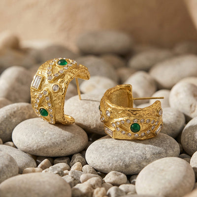 Pair of gold textured C hoop earrings with green stones on river pebbles