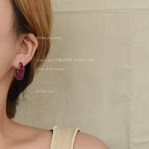 Purple resin C-shape hoop stud worn on ear close-up