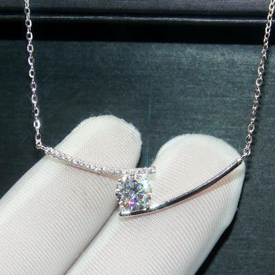 White gold curved bar smile pendant held in gloved hand close-up