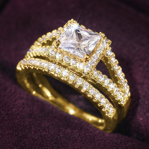 Gold-tone princess halo bridal ring set on deep purple fabric